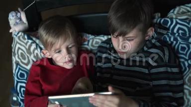 两个孩子晚上在家使用<strong>平板电脑</strong>。 在黑暗的房间里有<strong>平板电脑</strong>的兄弟。 孩子们，孩子们在<strong>平板电脑</strong>上<strong>玩</strong>游戏